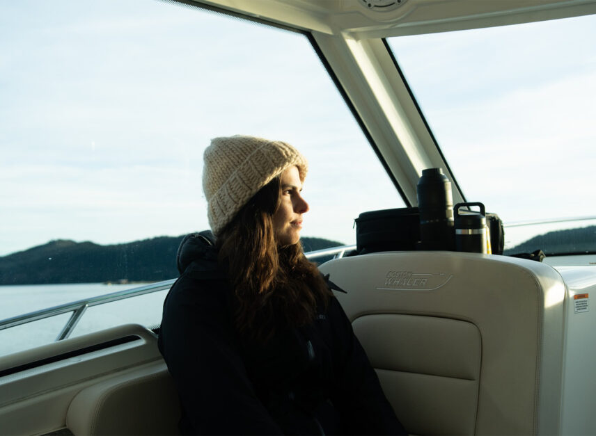 Woman enjoying a private boat ride with mountain views on the way to the floating sauna in Tofino