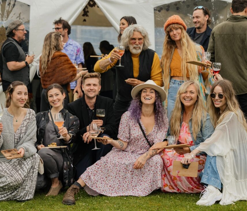 A group of friends smiling with wine glasses and classy food in hand
