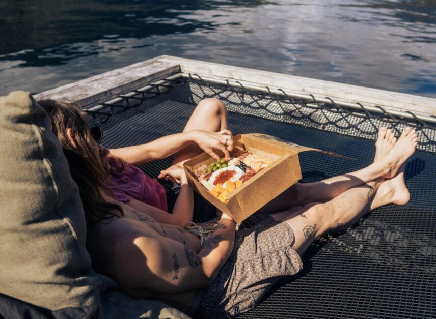 Couple enjoying a Bake Shack grazing board on the floating sauna hammocks