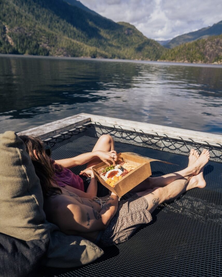 Couple eating food on a hammock on the remote floating sauna
