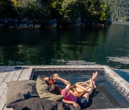 A couple in a hammock eating food at the Remote Floating Sauna