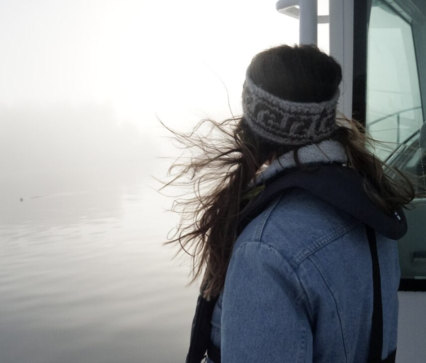 Woman on a boat looking out over the foggy winter ocean
