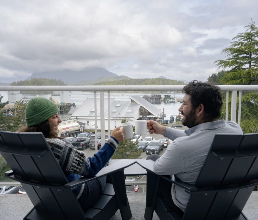 Two friends cheersing their hot chocolate on a balcony with a view