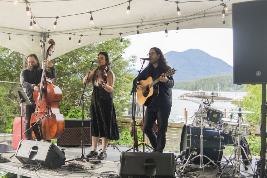 Band playing on an outdoor stage with views of Clayoquot Sound